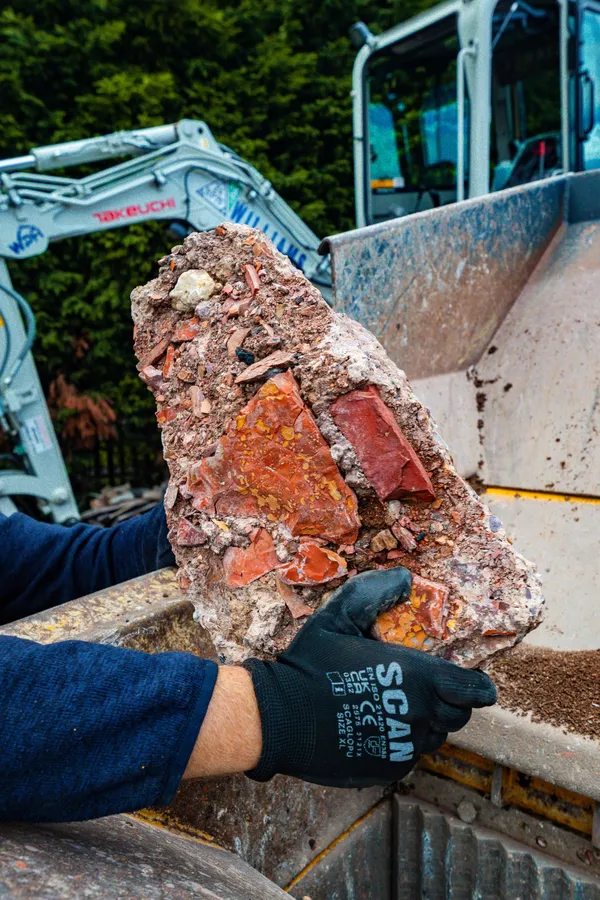 Old red brick held over the crusher jaw