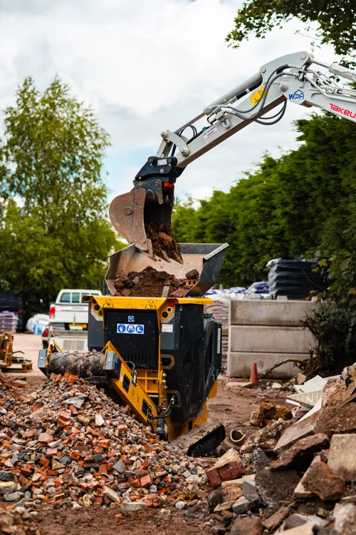 Mini excavator feeding rubble into the CR450 hopper