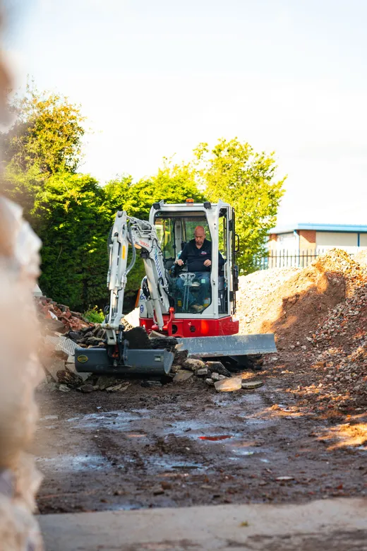 Mini excavator working a demolition heap on a plot